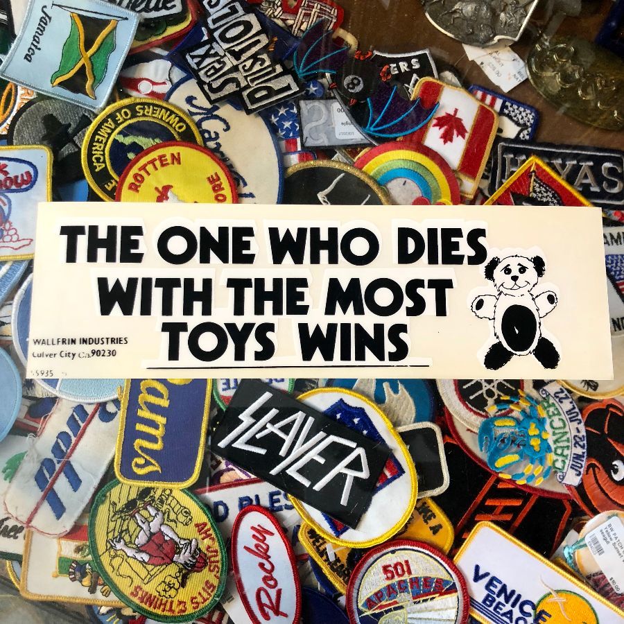 product details: THE ONE WHO DIES WITH THE MOST TOYS WINS - REMOVABLE VINYL BUMPER STICKER photo