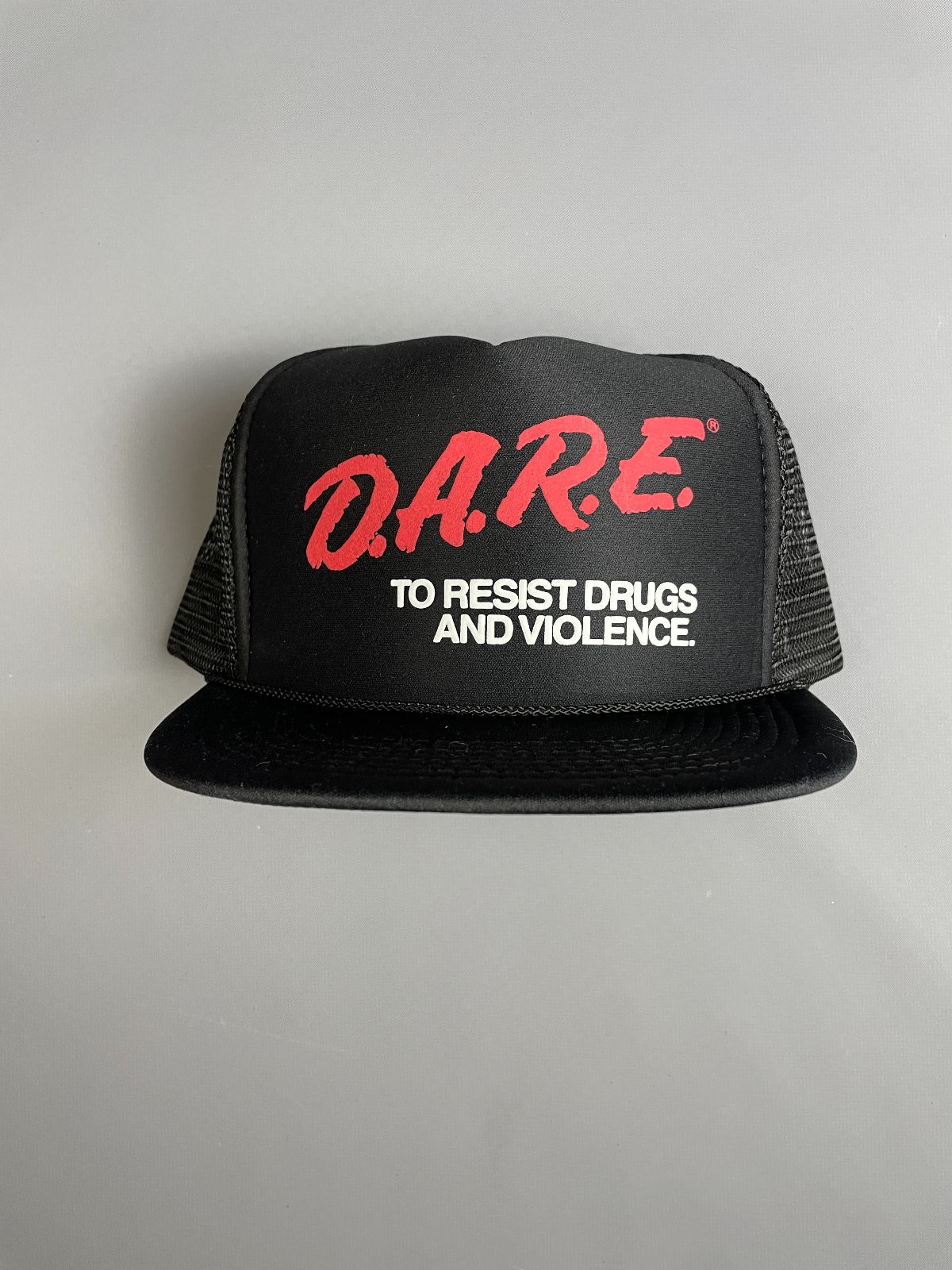 product details: DARE TO RESIST DRUGS AND VIOLENCE LOGO GRAPHIC MESH SNAPBACK TRUCKER HAT photo