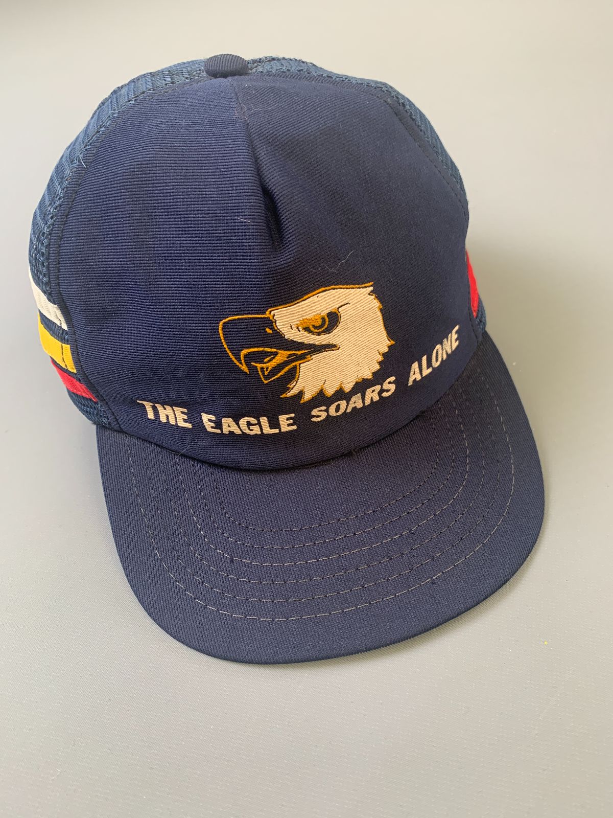 product details: THE EAGLE SOARS ALONE THREE STRIPE SNAPBACK TRUCKER HAT photo