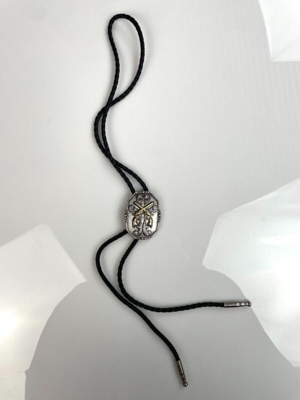 2-TONE ORNATE CROSSED PISTOL PLACARD BOLO TIE, BRAIDED LEATHER CORD